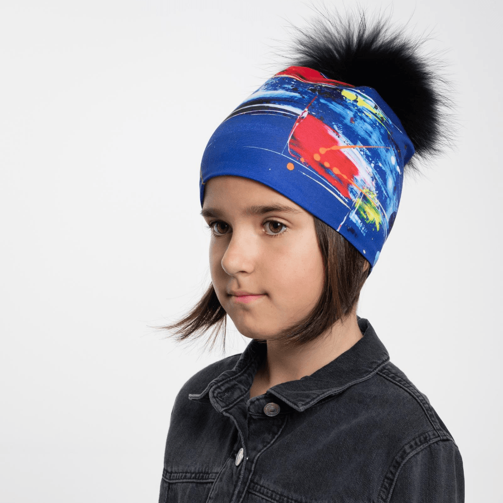 Une jeune fille portant la Tuque Bleue Abstrait avec un pompon noir amovible.