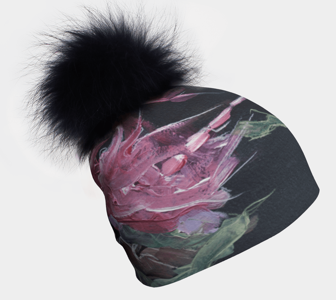 Gros plan d'une tuque style baroque avec un pompon noir et une peinture florale rose.