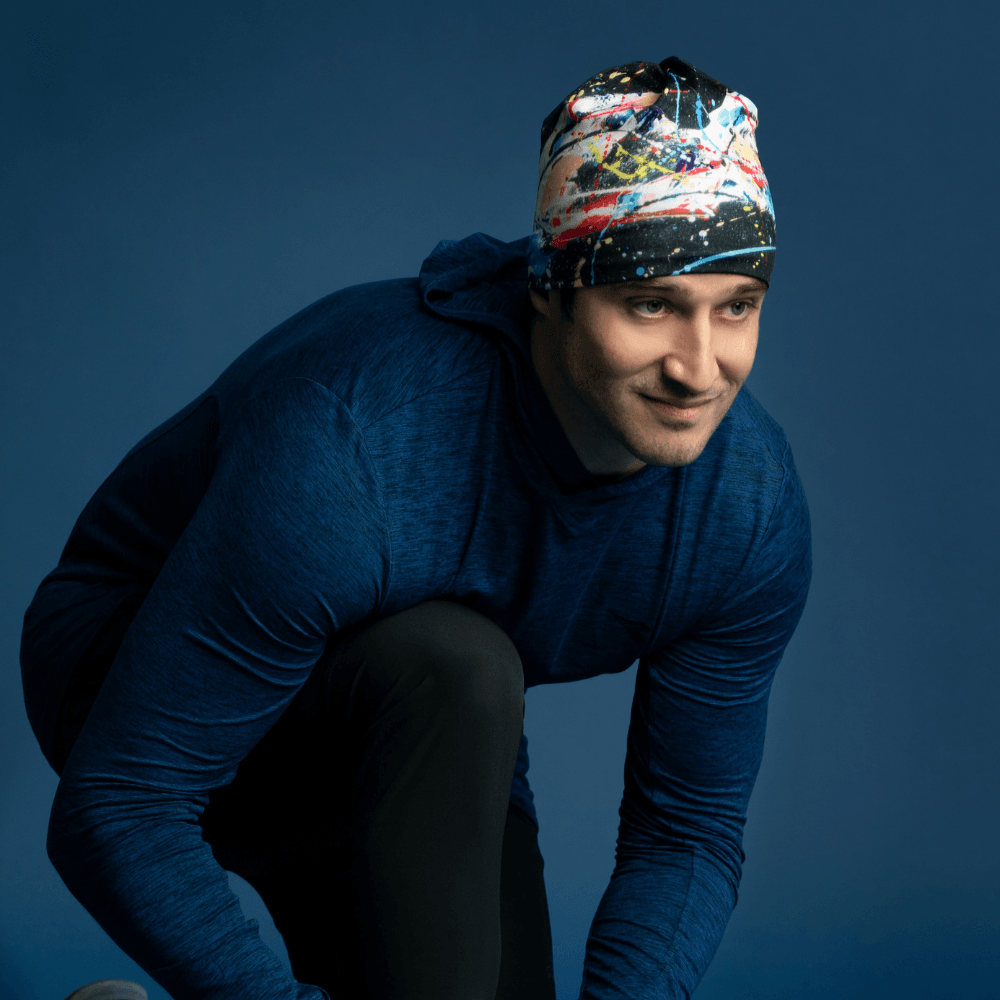 Homme portant la tuque Cheval Noir, accroupi comme s'il se nouait les lacets pendant une course.