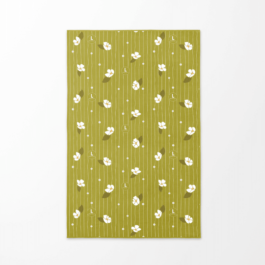 Le revers de la serviette de plage artistique Chrysalide, avec un fond vert doux et des motifs floraux blancs et des lignes verticales.