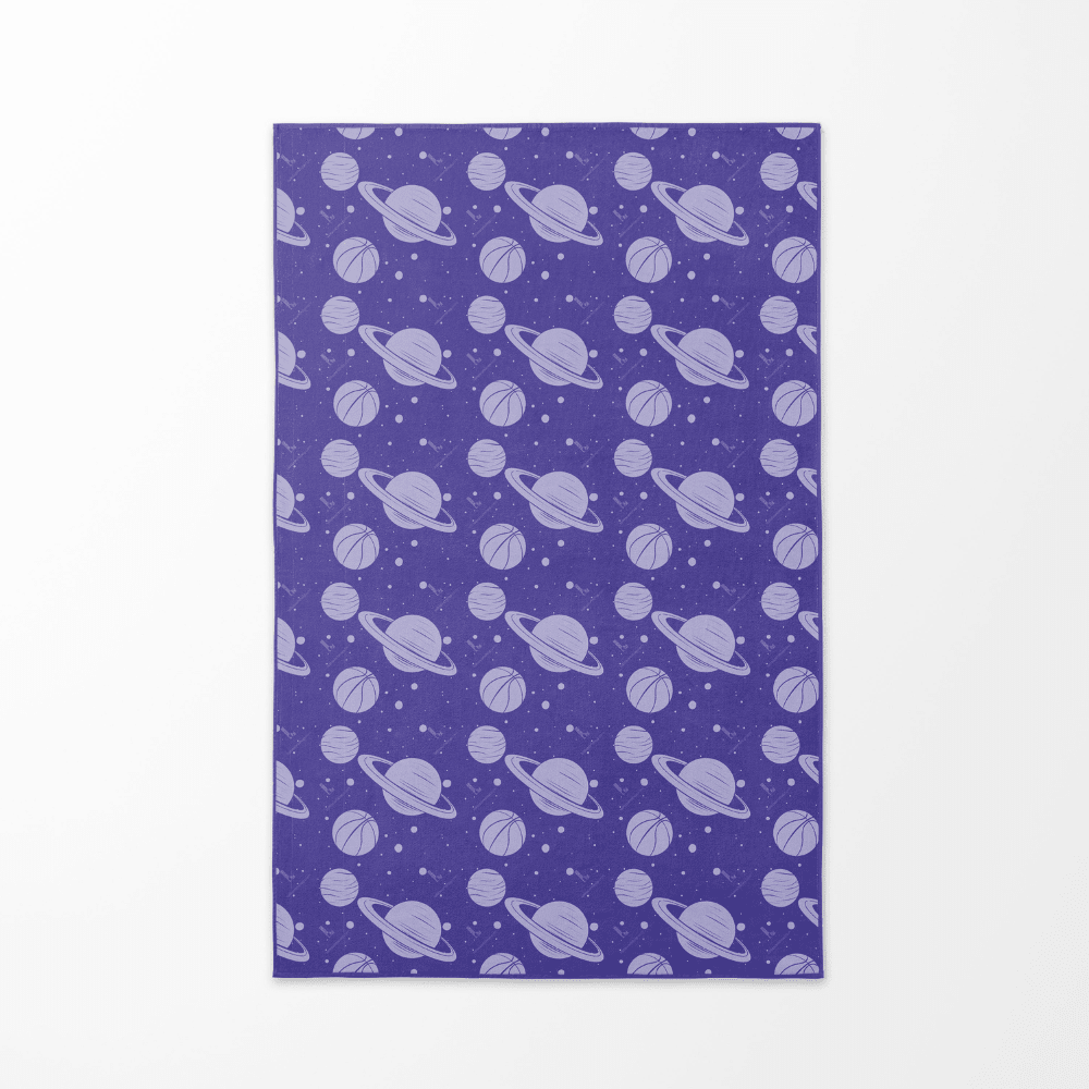 Back side of the Cosmic Slam beach towel with a repeating pattern of purple planets and basketballs on a starry background.