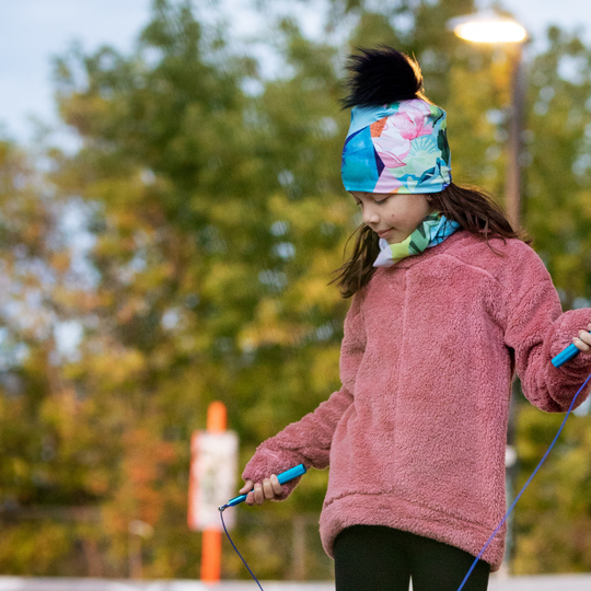 Jeune fille portant une tuque et un cache-cou assortis, jouant à la corde à sauter à l&