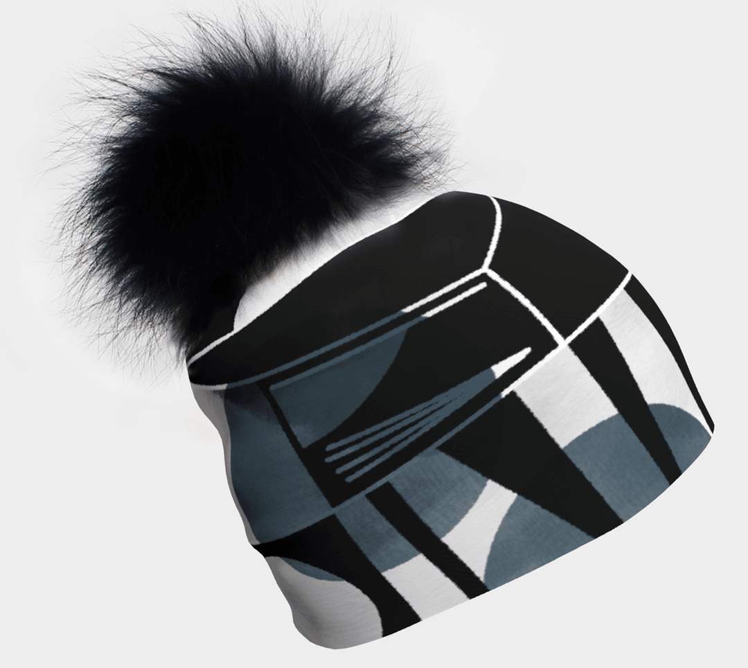 Gros plan d'une tuque à motif géométrique noir et gris avec un gros pompon noir sur fond blanc.