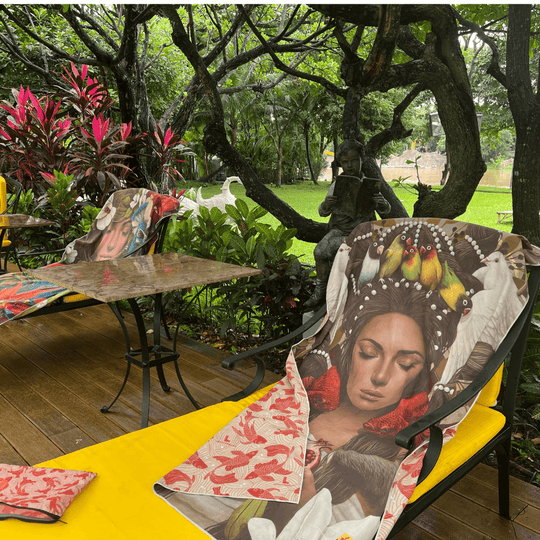 La serviette Guerrière Pacifique drapée sur des chaises longues jaunes et une table dans un jardin extérieur.