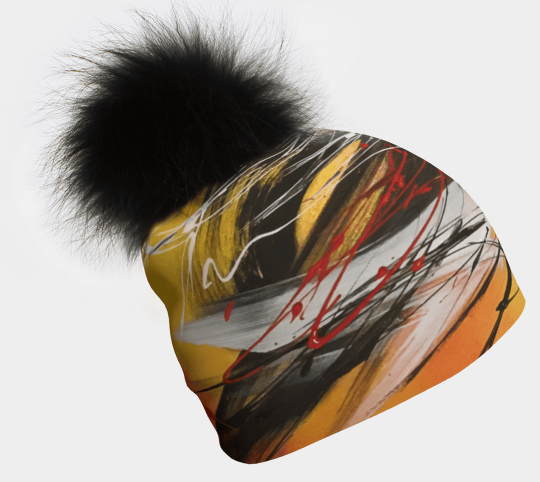 Tuque Le Coeur avec un gros pompon noir, exposant un art abstrait jaune, noir et rouge.