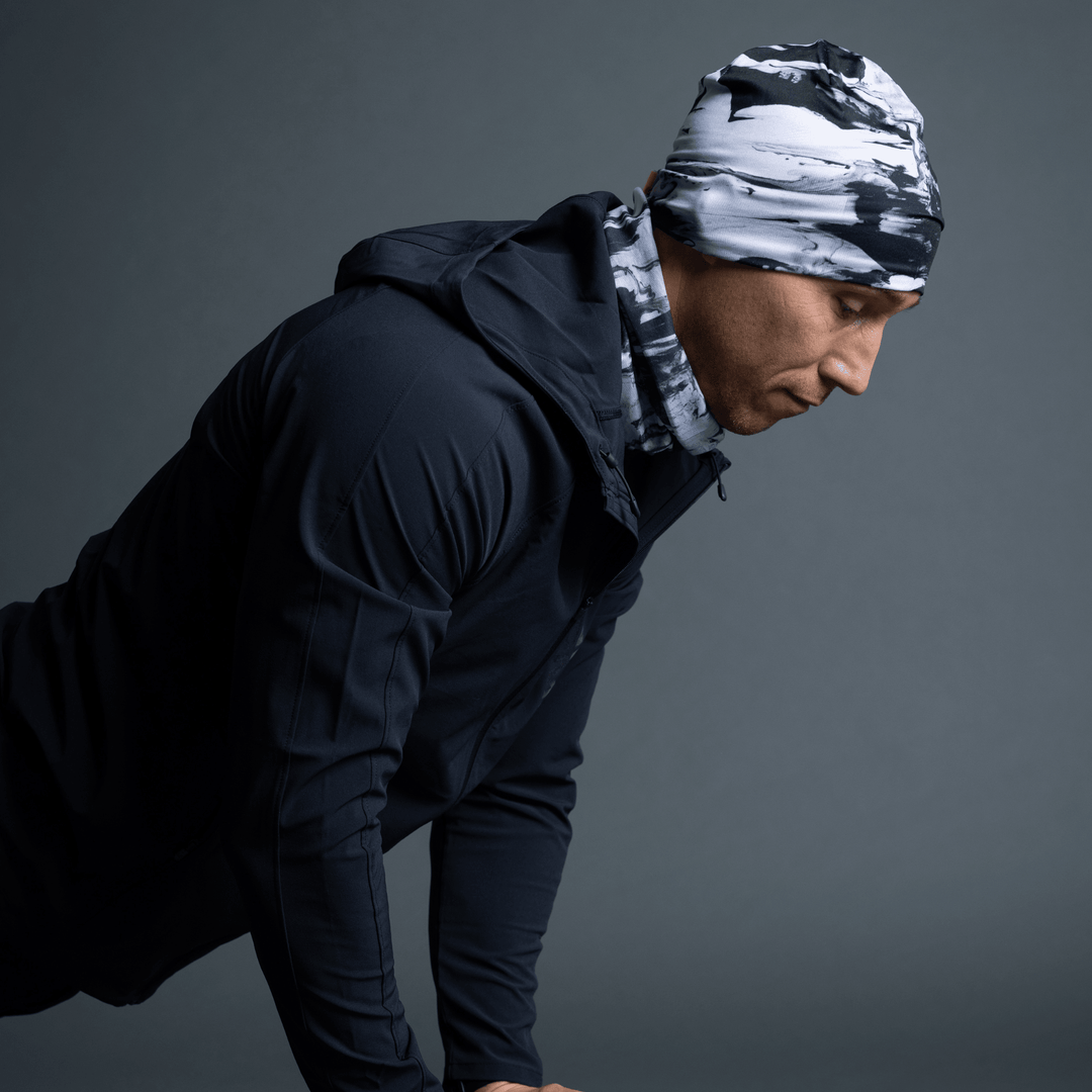Homme portant une tuque et un cache-cou assorti au motif abstrait noir et blanc, regardant sur le côté.