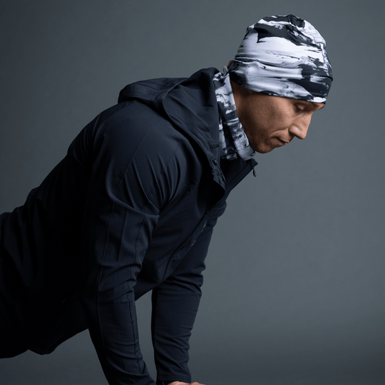 Homme portant une tuque et un cache-cou assorti au motif abstrait noir et blanc, regardant sur le côté.