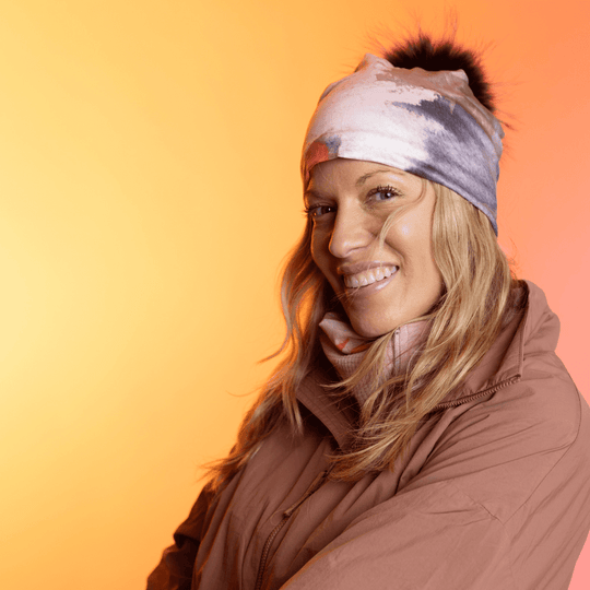 Smiling woman wearing the Pink &amp; Flames Beanie with a black pompom.