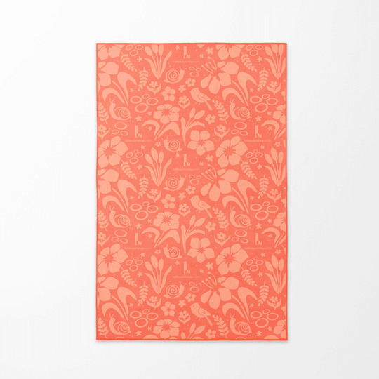 Le motif floral corail de la serviette de plage Pluie Joueuse pour enfants affiché à plat sur un fond blanc.