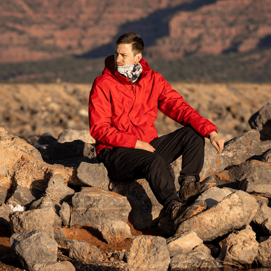 Un homme en veste rouge assis sur des rochers à l&