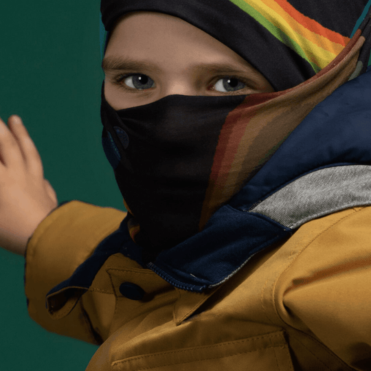 Enfant portant une veste jaune et une tuque bleue, avec le Cache-cou Polar Flying Saucers remonté comme protection faciale
