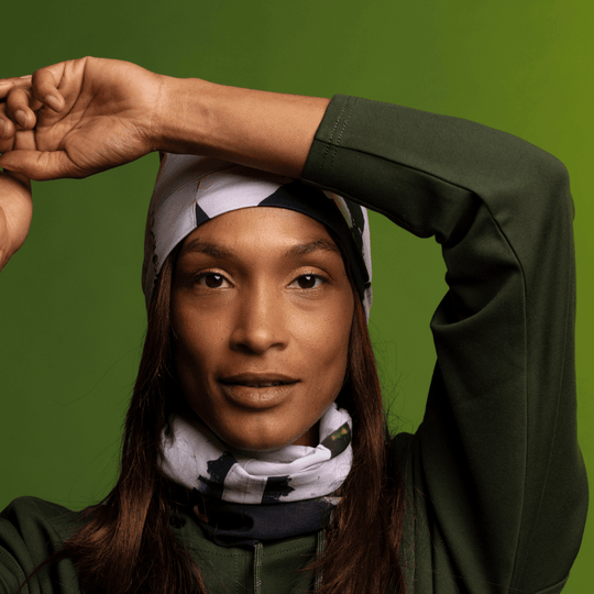 Femme portant le Tube multifonction POLAR Motif matelassé moderne en tuque et cache-cou, style avec un sweat à capuche vert.