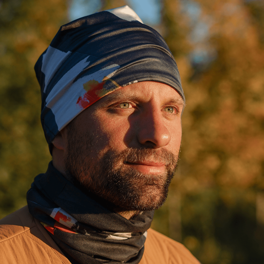 Homme à l'extérieur portant un tube au motif artistique coloré en tuque et en foulard.