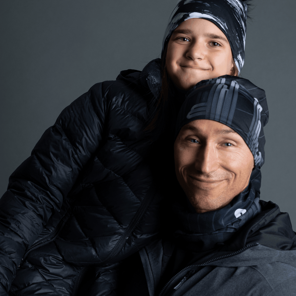 Homme et enfant portant des tuques Radio City assorties et des manteaux d'hiver, souriant.