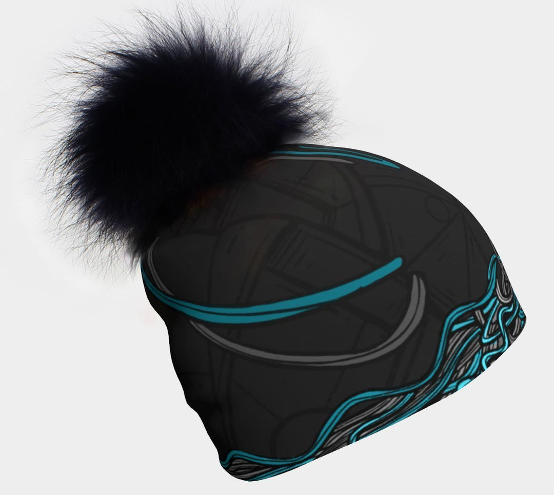 Tuque à motif noir et bleu avec un grand pompon noir moelleux sur fond blanc.