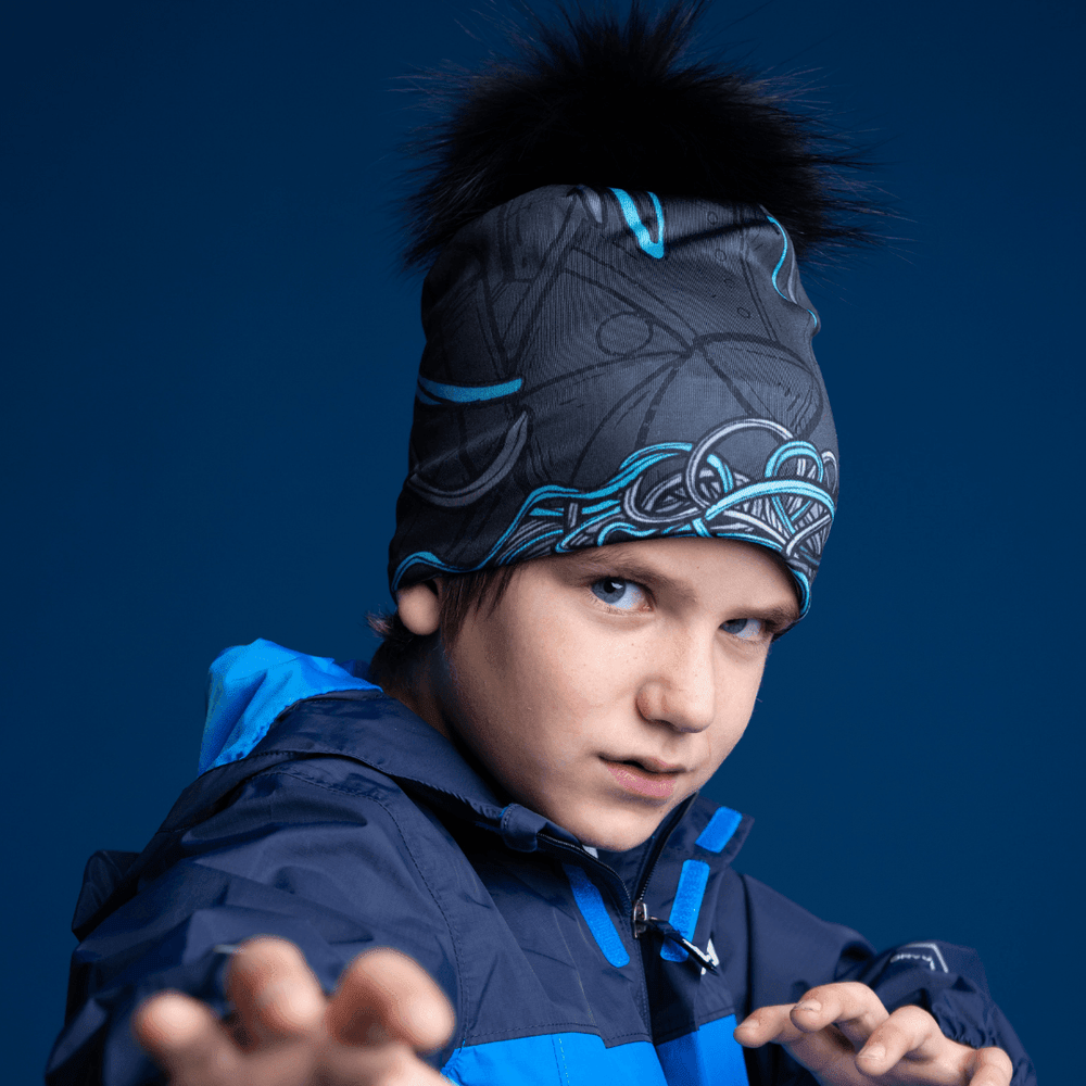 Gros plan sur un garçon portant la tuque Robocats noire et bleue sous une veste à capuchon bleue, regardant directement la caméra.