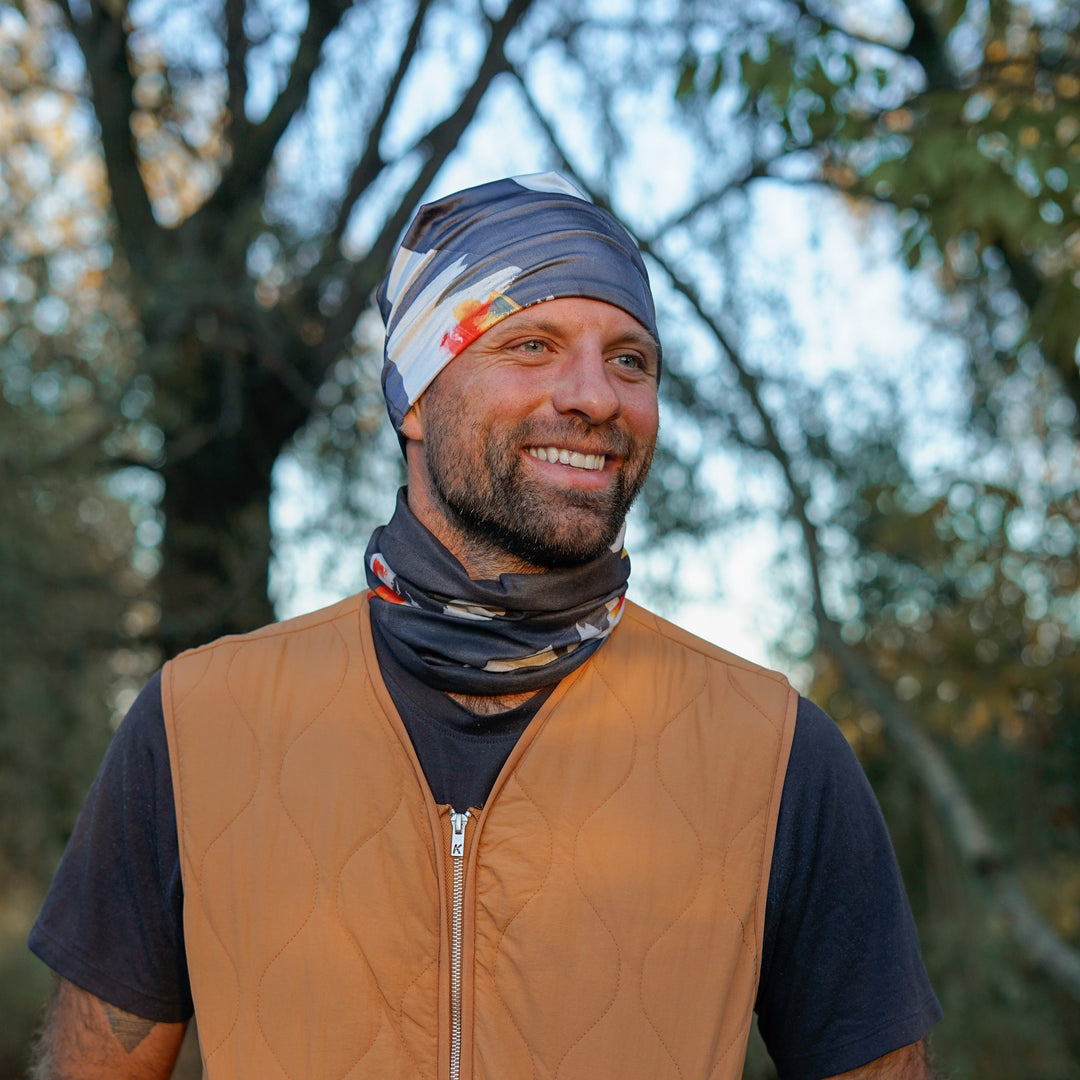 Homme portant un tube bandana en bandeaux et cache-cou, souriant à l&