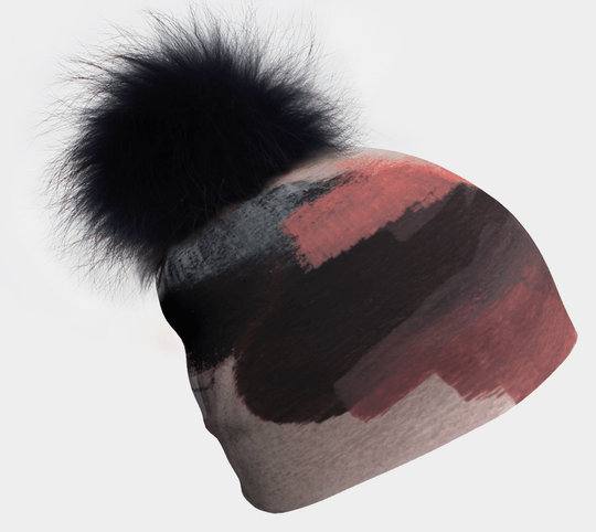 Tuque avec pompon noir et motif abstrait de coups de pinceau en corail, gris et noir.