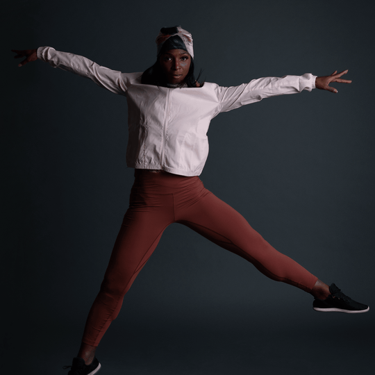 Femme en tenue sportive portant la Tuque Vie en Rose, capturée en plein saut.