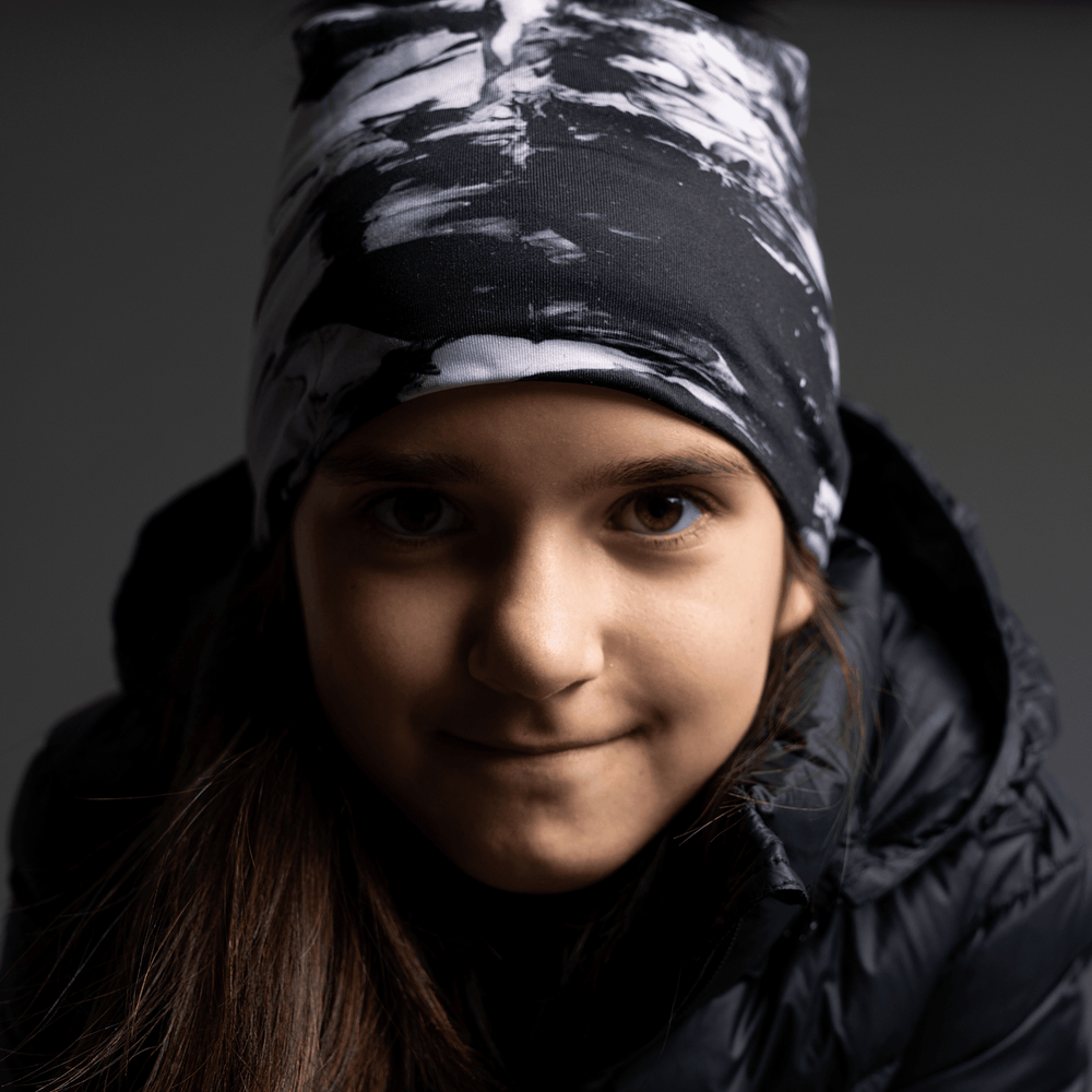 Jeune fille portant la tuque abstraite noir et blanc, regardant devant.