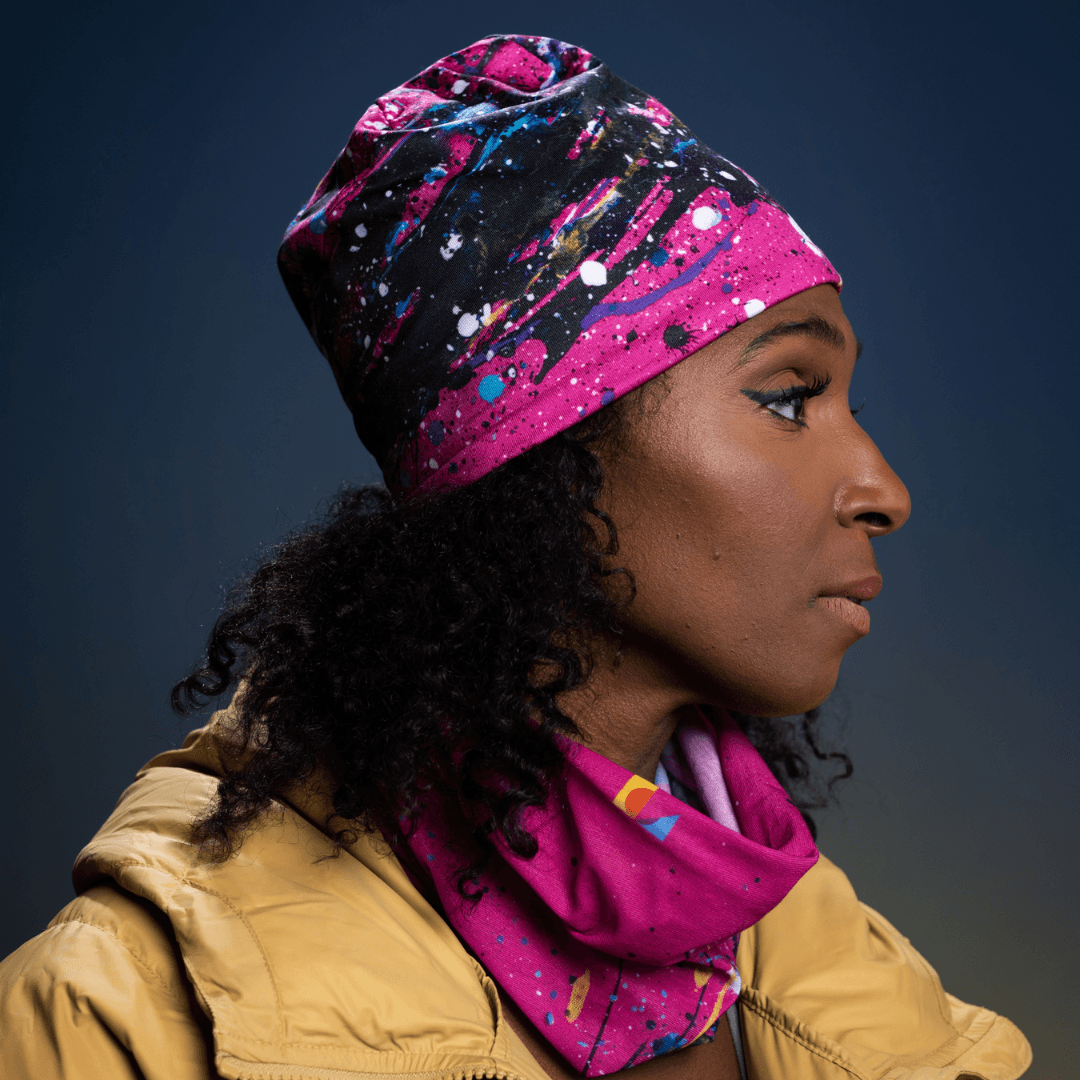 Woman wearing the pink abstract print tube as a beanie and a neck gaiter.