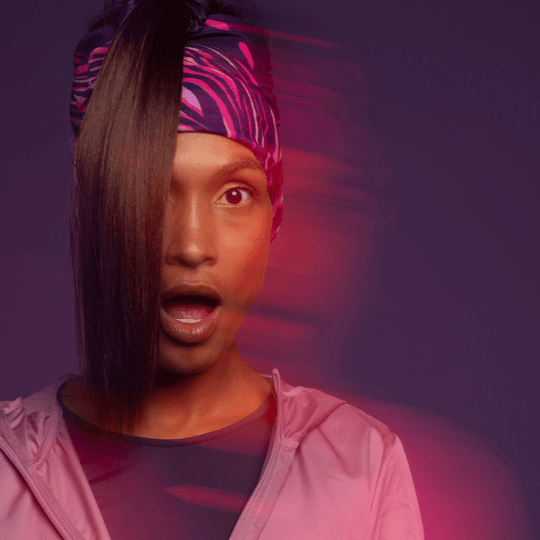 Woman making a surprised face and wearing the Magenta Owl Multifunctional tube as headband for the Lalita&