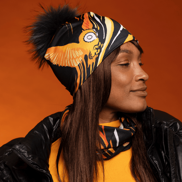 Woman wearing the Orange Owl multifunctional tube with assorted pompom beanie by Julie Rocheleau for the Lalita's Art Shop 24 collection